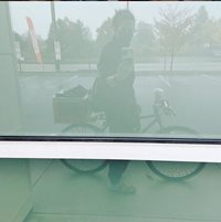 Person on a bike taking a picture of their reflection in a window.