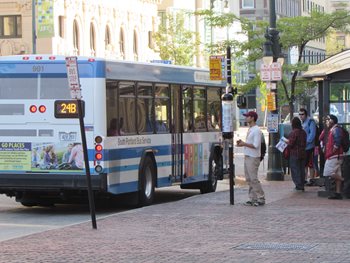 People standing a bus stop waiting to get on the public transport bus.